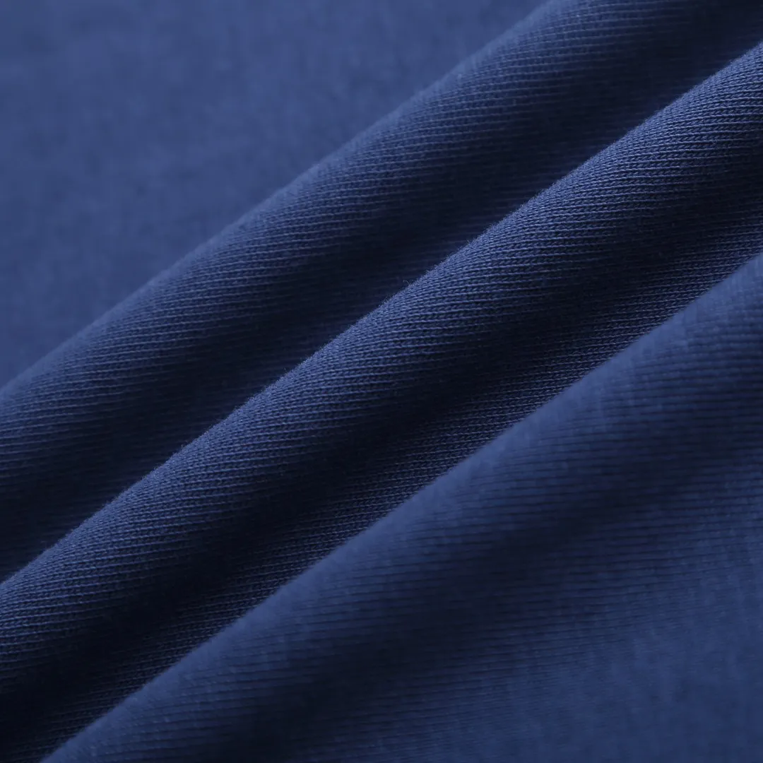 AMI Love A Embroidered Short Sleeve Fabric Selection: High-count pure cotton is selected, with moderate weight and natural drape. The cotton fiber itself has good moisture absorption and breathability, which can quickly absorb sweat and dissipate it outwards. At the same time, it feels soft and delicate, and it is non-itchy when worn next to the skin. After the pre-shrinking process, the washing shrinkage is greatly reduced, and it is not easy to deform after repeated machine washing. Craftsmanship: 1: The advanced computing system of imported embroidery machines is used to depict the contour lines of the love A pattern. White embroidery thread and Tibetan Blue fabric form a soft contrast, with neat edges, no skipping lines, and no burrs. The pattern is full and three-dimensional, and the texture is delicate. 2. Make dark embroidery of letters of the same color on the back neckline, using embroidery threads of the same color as the fabric, which is low-key and not obtrusive, and does not destroy the overall simple style. The back of the embroidered product is flat and has no bulges, and will not irritate the skin, taking into account both beauty and wearing comfort. Sewing details: 1: The collar, cuffs, hem, and shoulder lines are all made of contrasting topstitching and double-turn craftsmanship. The neatly routed threads form a sharp contrast with the Tibetan Blue fabric and outline the outline of the clothes. 2: The internal seams of the clothes are all treated with overlocking technology, without excess burrs or threads, and the details are clean and tidy; the hem and cuffs are made with double-folding stitching technology, and the edges are smooth and not frizzy to avoid curling and curling when wearing. Accessories: One-to-one customized three-standard Size: S M L XL Style No. D 292